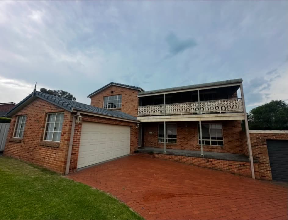 Brick home before, with cream garage door, posts and balcony
