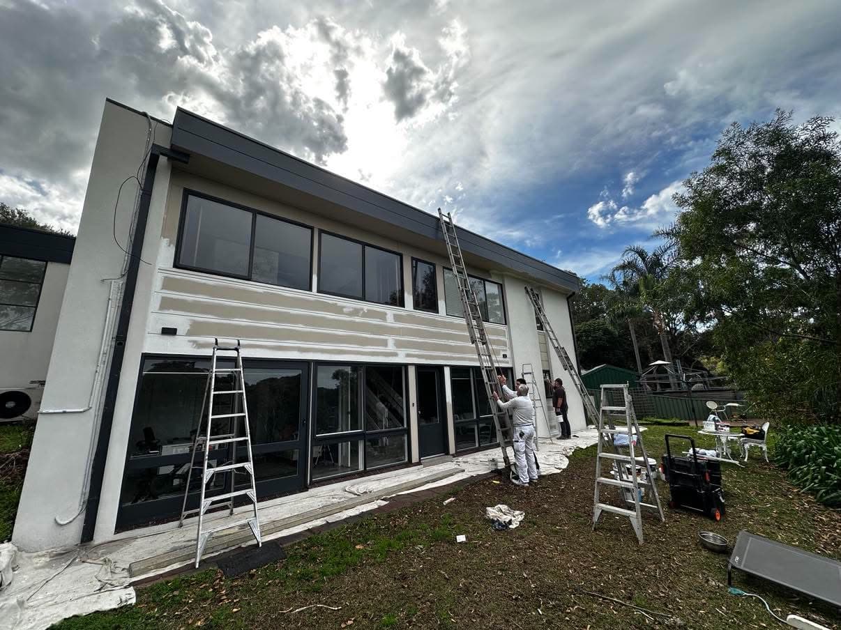 Two-storey house mid-repaint with ladders up